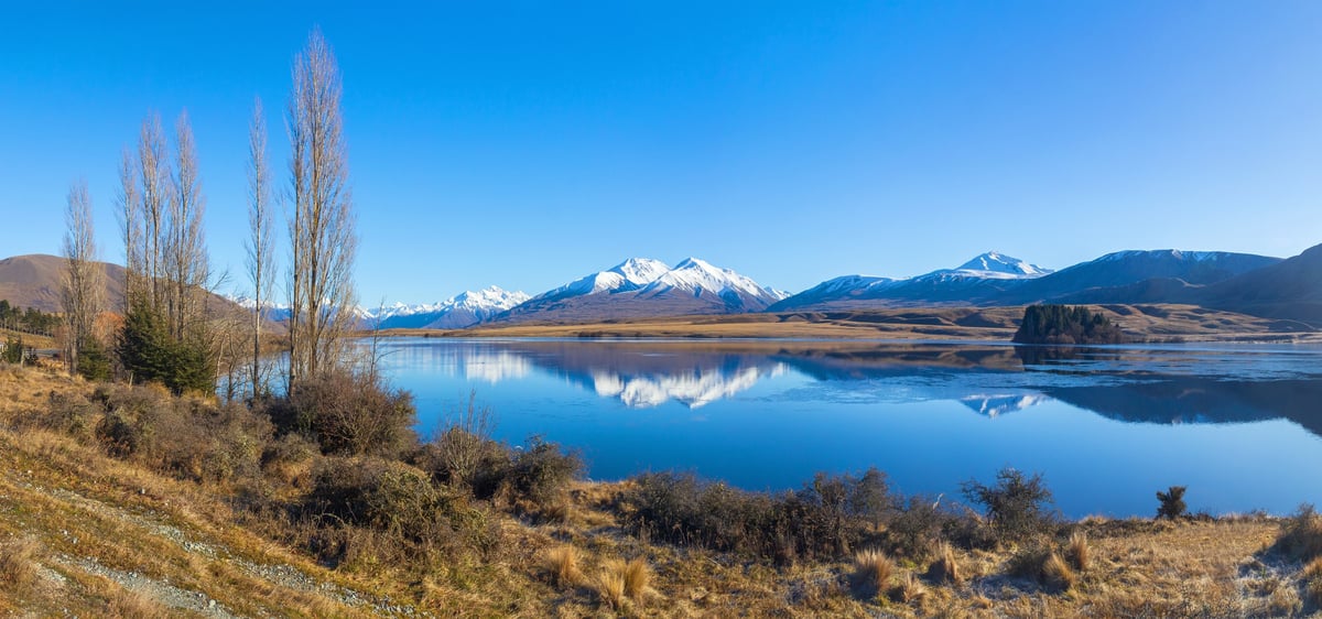 Calm lake surrounded by snow-capped mountains on a clear winter day