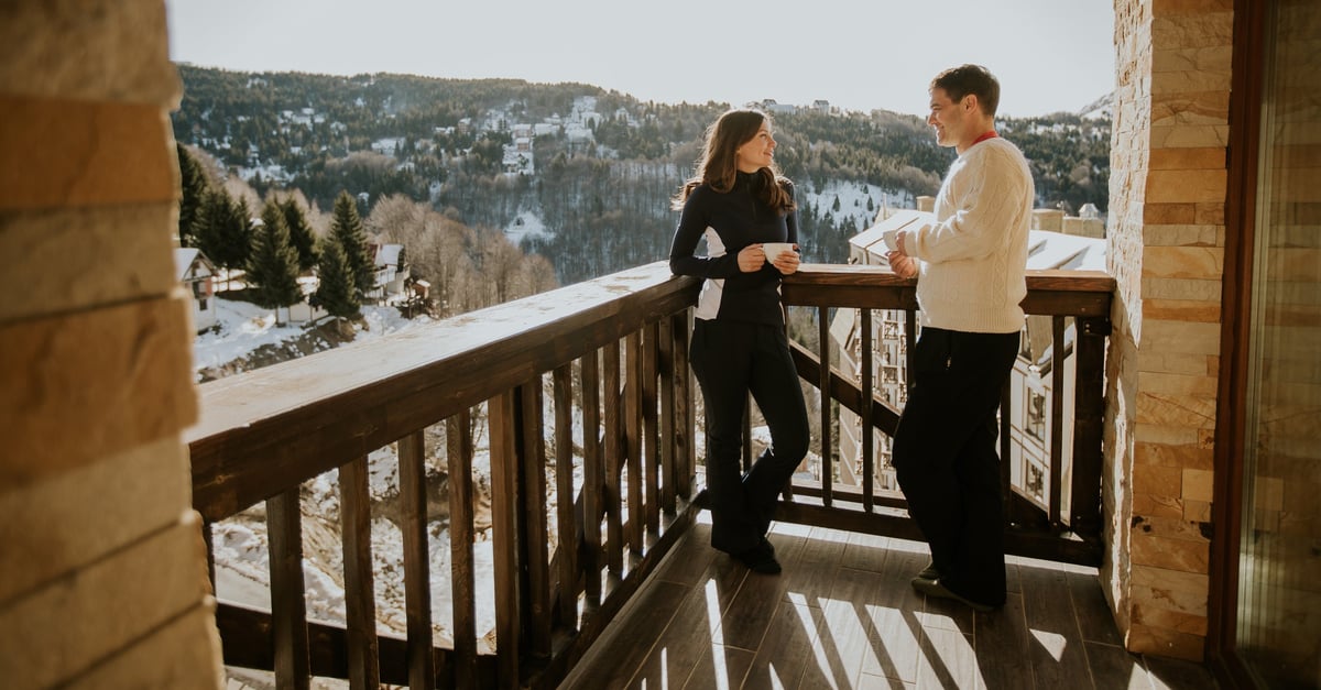 Couple standing together overlooking snowy mountains at sunset