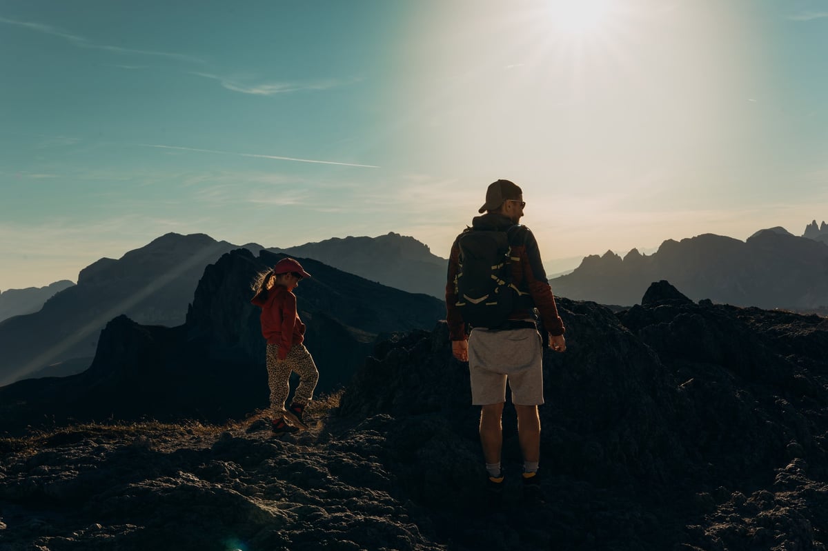 Hikers on a mountain ridge watching sunrise over alpine peaks