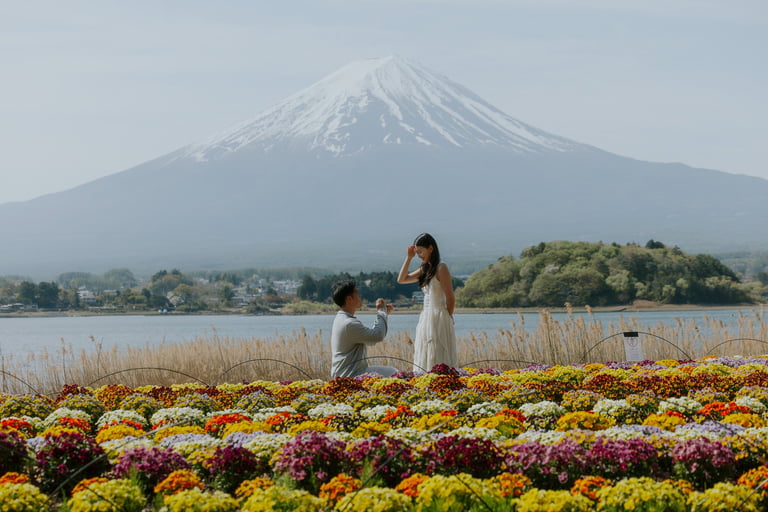 Woman and child in flower field with Mount Fuji and lake in background on misty day