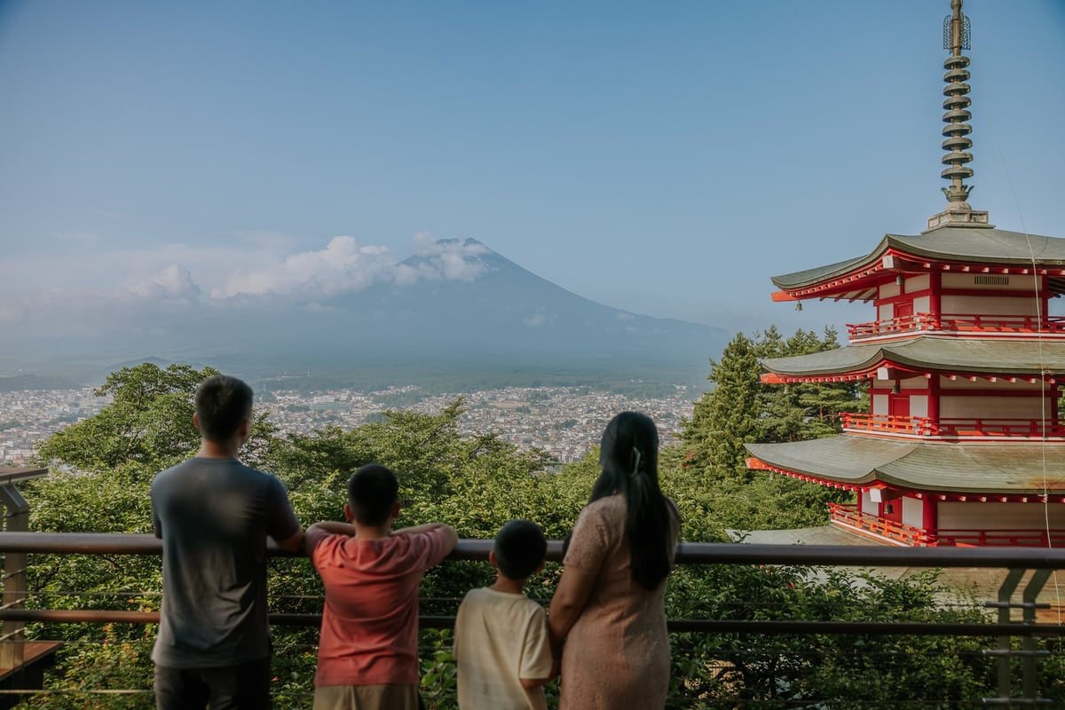 Four people viewing Mount Fuji from an observation point next to a red Japanese pagoda