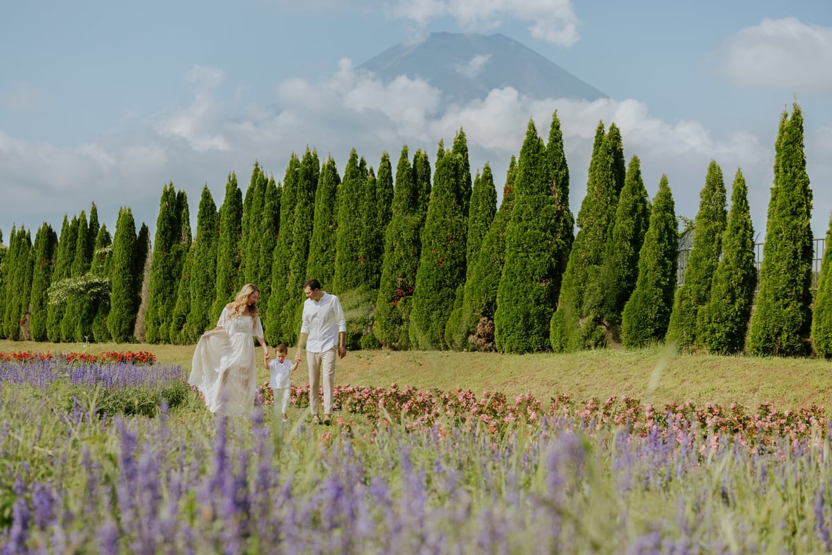 Couple walking through lavender field with cypress trees and mountain in background