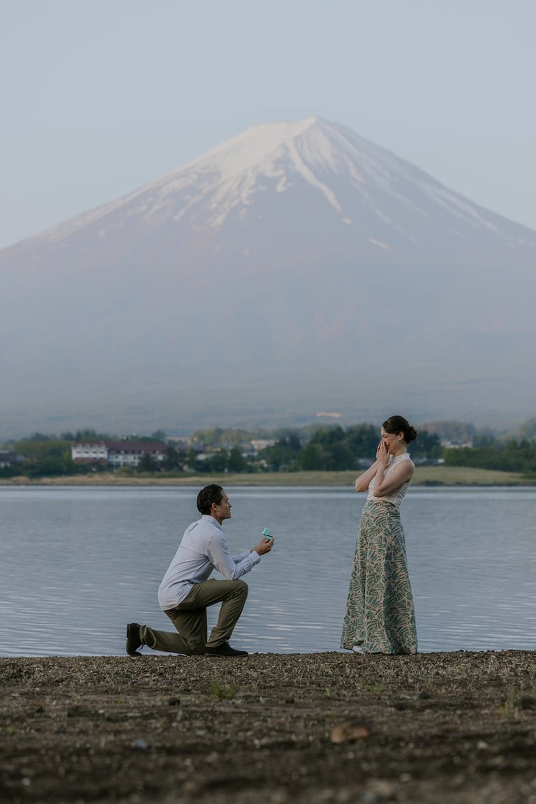 Man proposing to woman on a beach with Mount Fuji and lake in the background